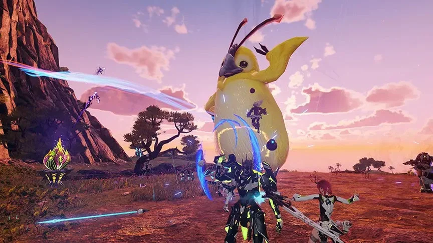 夕焼け空の下、広大なフィールドで複数のプレイヤーキャラクターが巨大な黄色いモンスターと対峙しているゲームのスクリーンショットです。