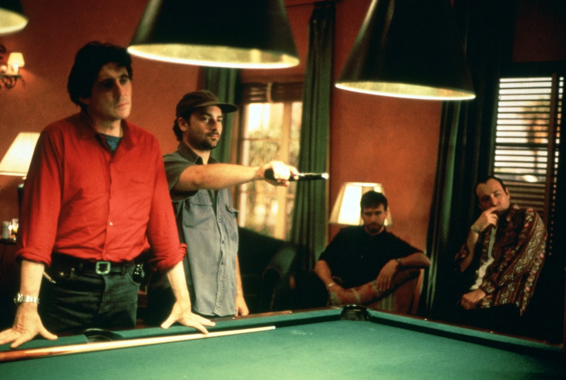 プールバーのような場所で数人の男性がビリヤード台を囲んでいる