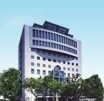 青い空を背景に立つ、特徴的なデザインの現代的なオフィスビルです。