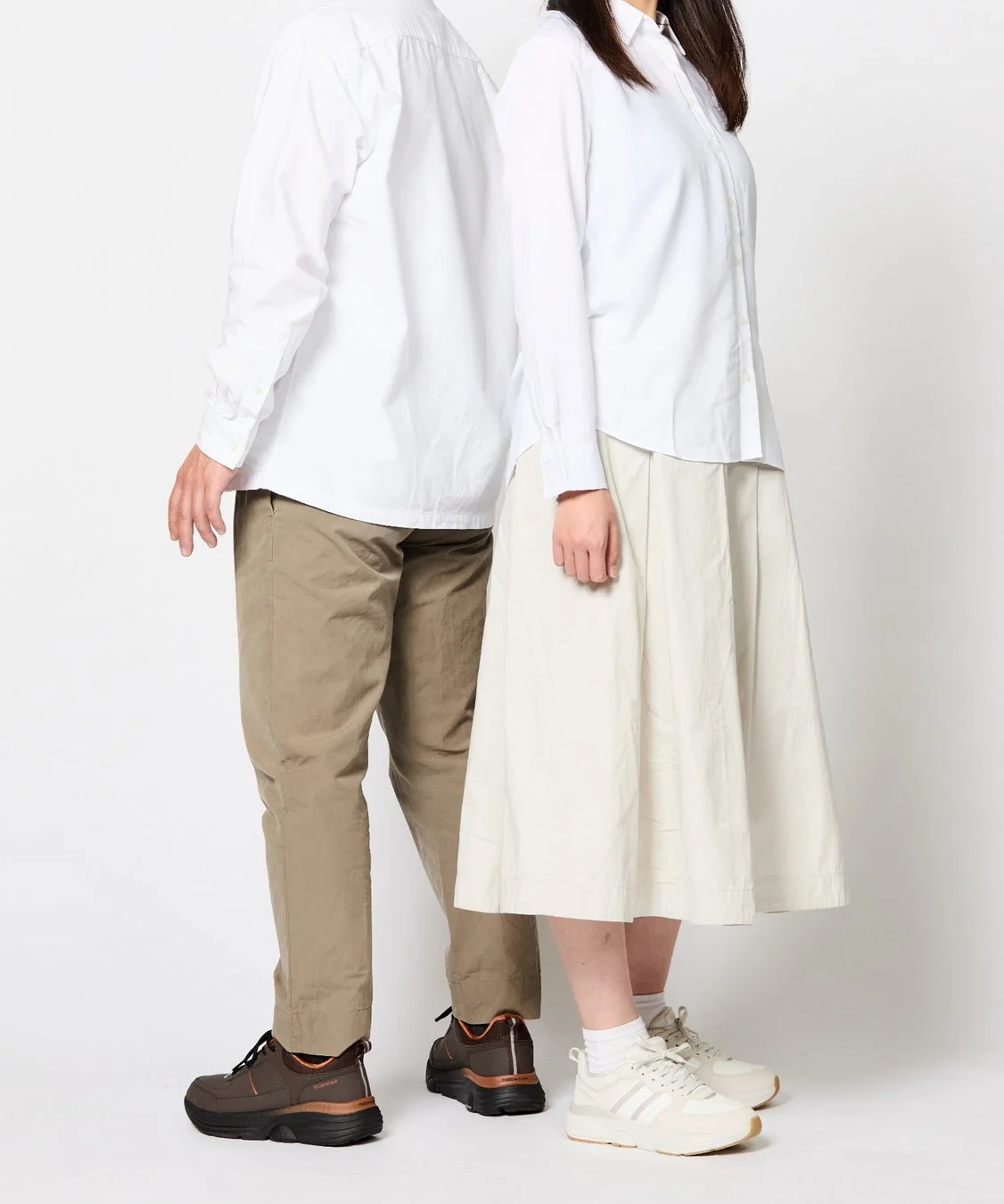 白いシャツとニュートラルカラーのボトムスを着用した男女