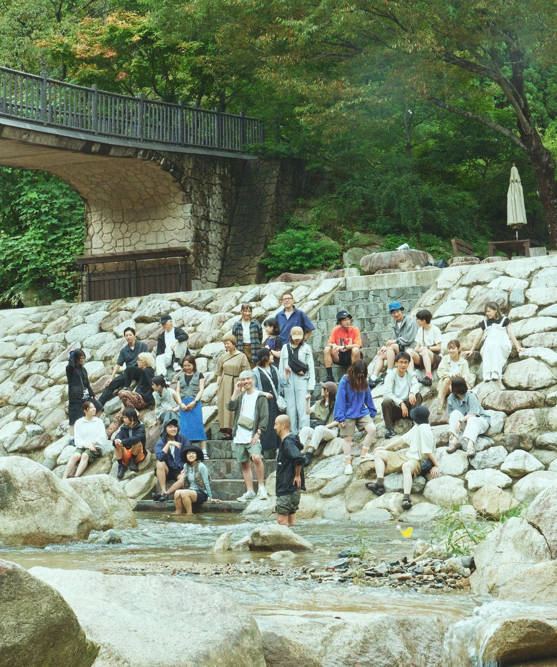 自然豊かな川辺に多くの人々が集まっている様子。