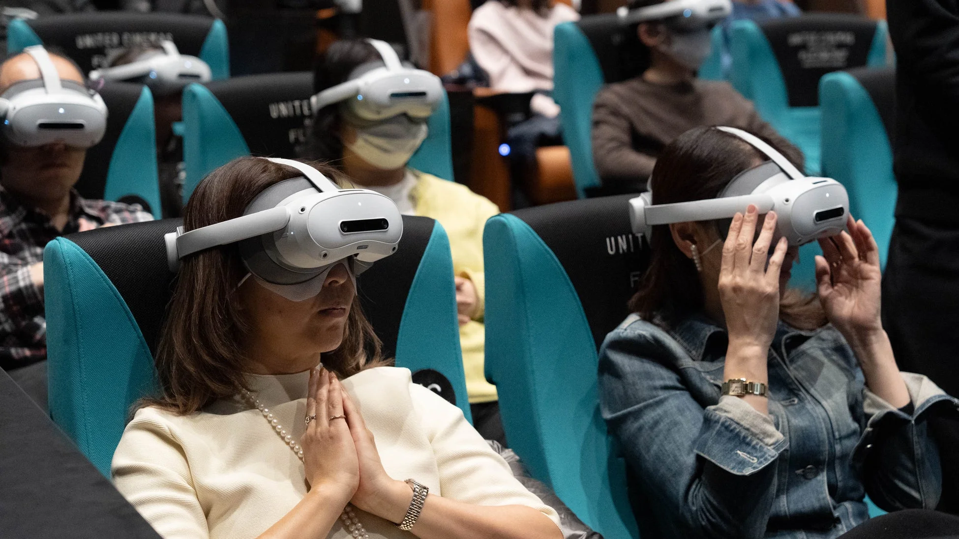 VRヘッドセットを装着した観客たちが、手を合わせるなどして没入体験している様子