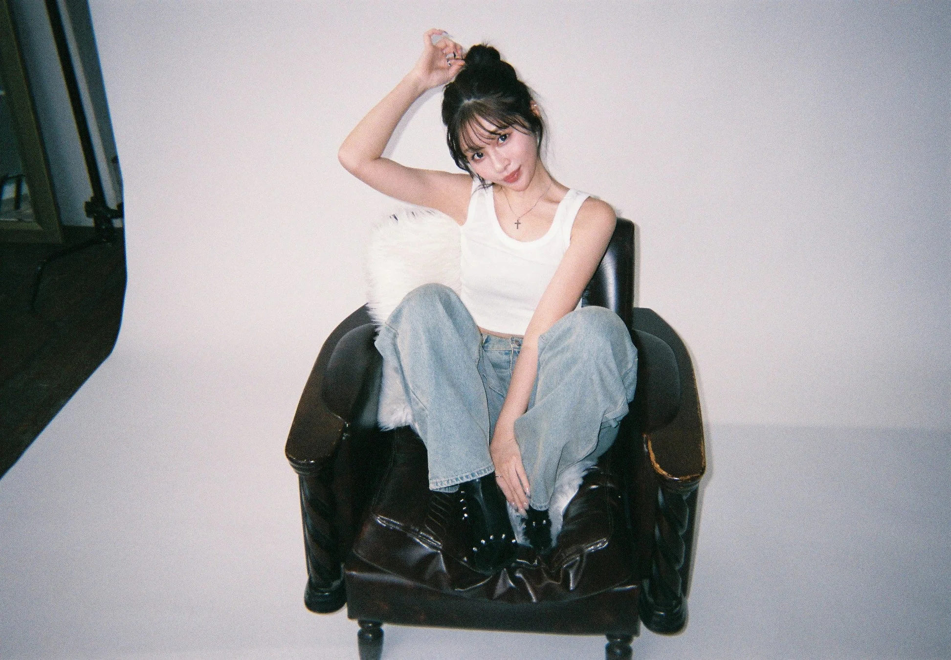 白いタンクトップとジーンズ姿のすずさんが椅子に座っている