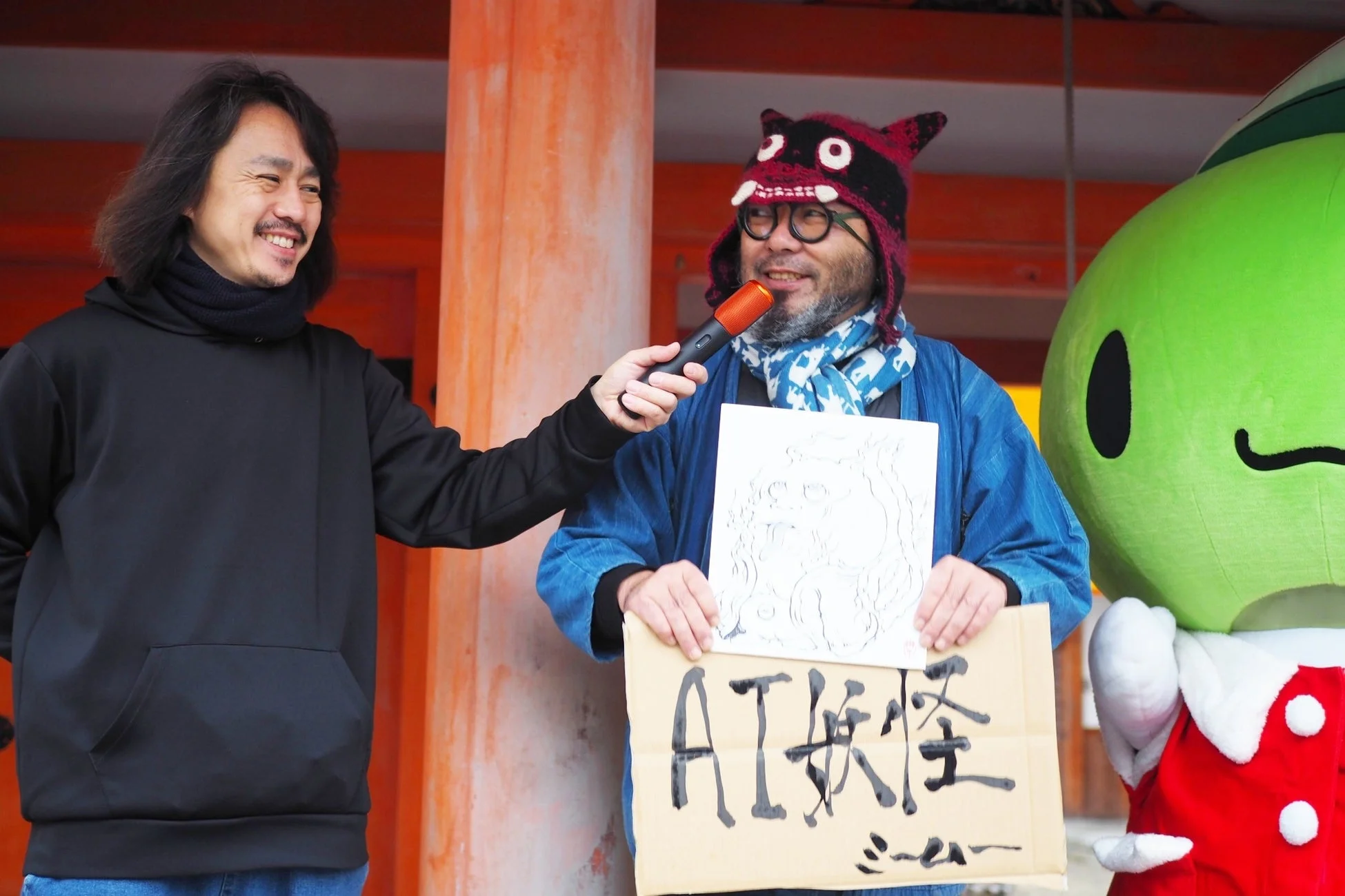 AI妖怪のボードを持つ柳生忠平館長とインタビューの様子