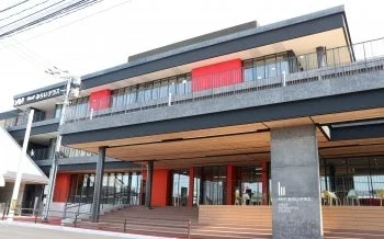 黒と赤を基調としたモダンなデザインの多層階の建物です。「MHP みらいテラス」という名称が見え、新しい世代の街を象徴するような複合施設であることが伺えます。