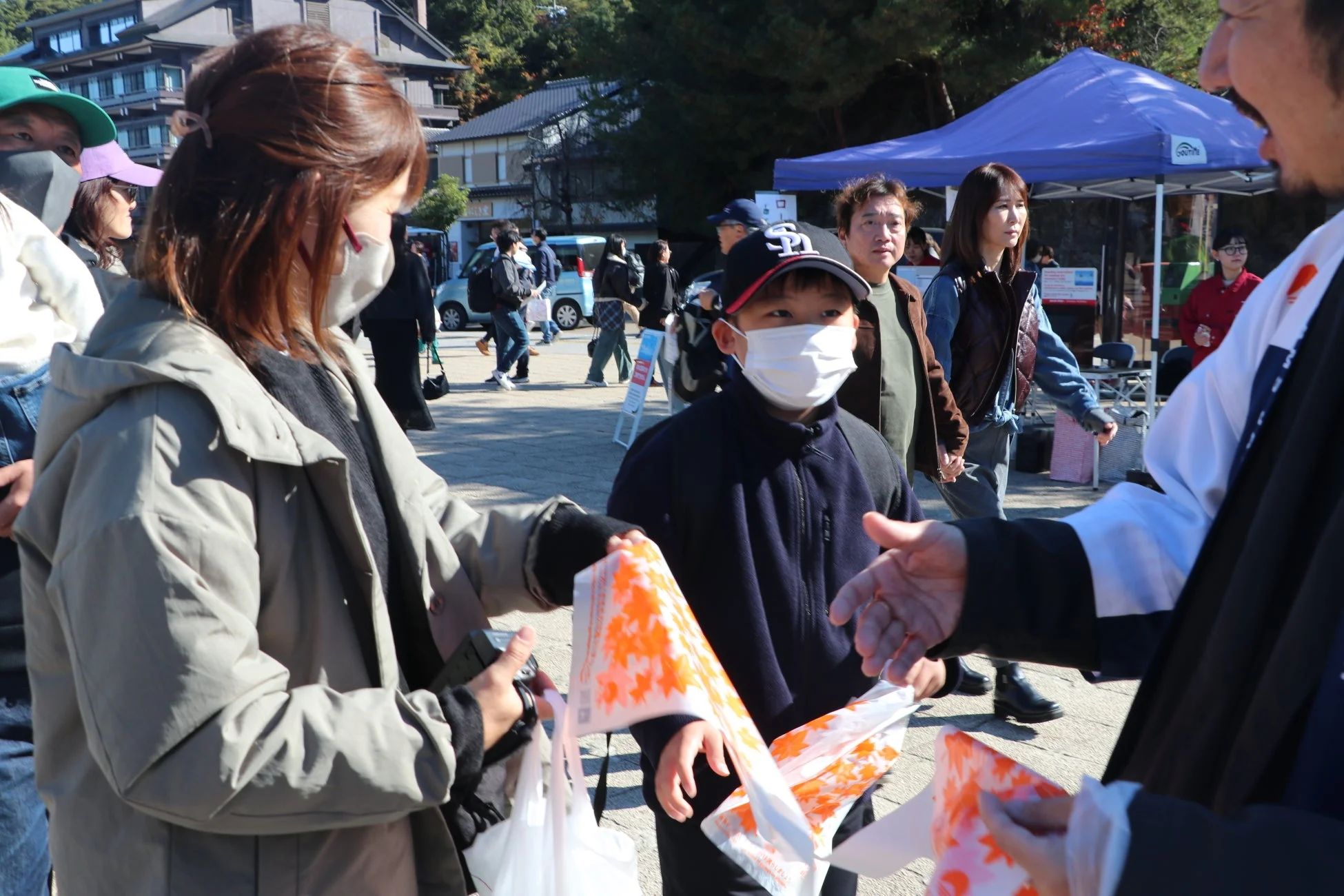 人々が紅葉柄の袋を受け取っている様子