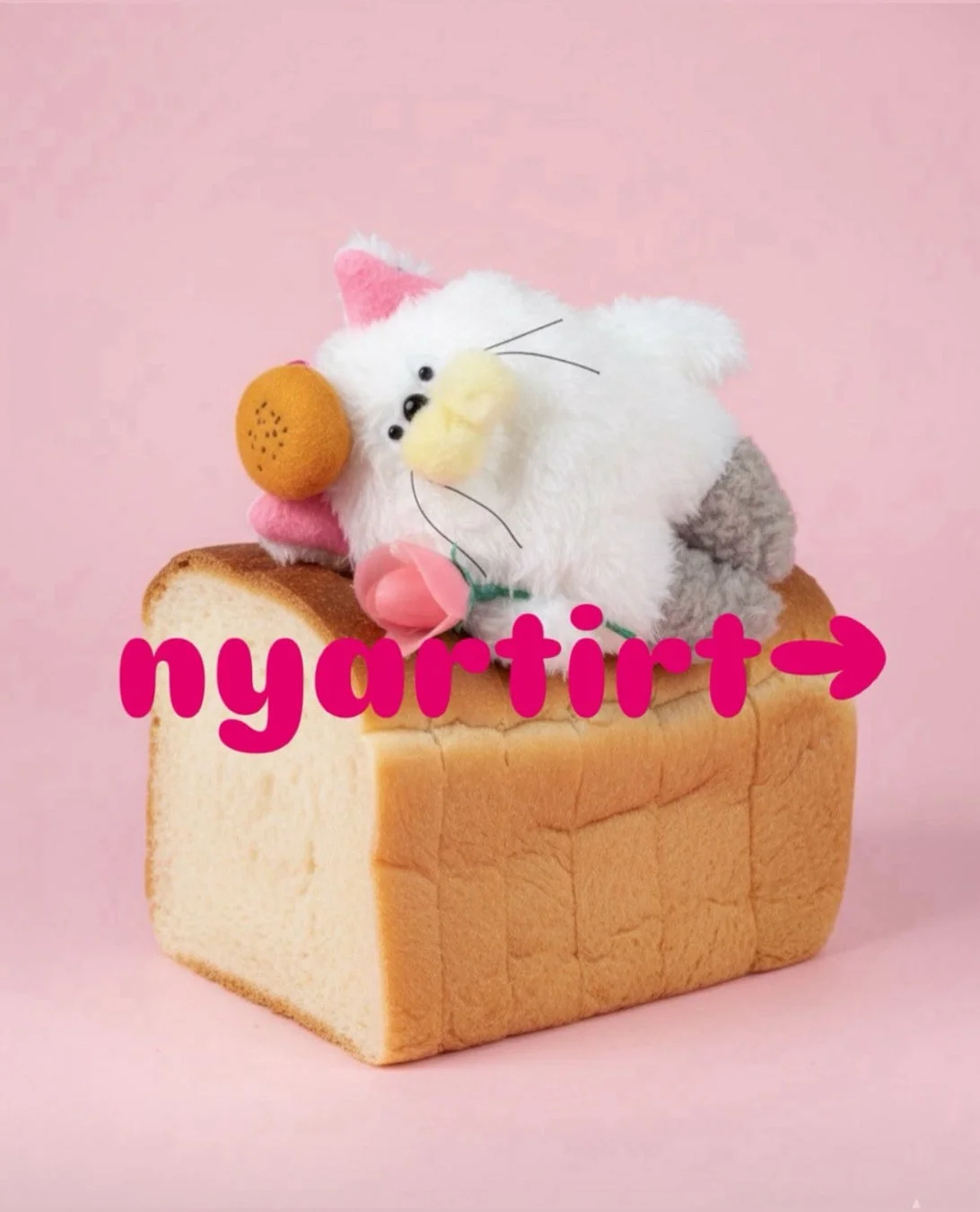 ピンクの背景に置かれた食パンの上に、白いふわふわの猫のぬいぐるみが乗っています。ぬいぐるみはオレンジとピンクのバラを持っています。