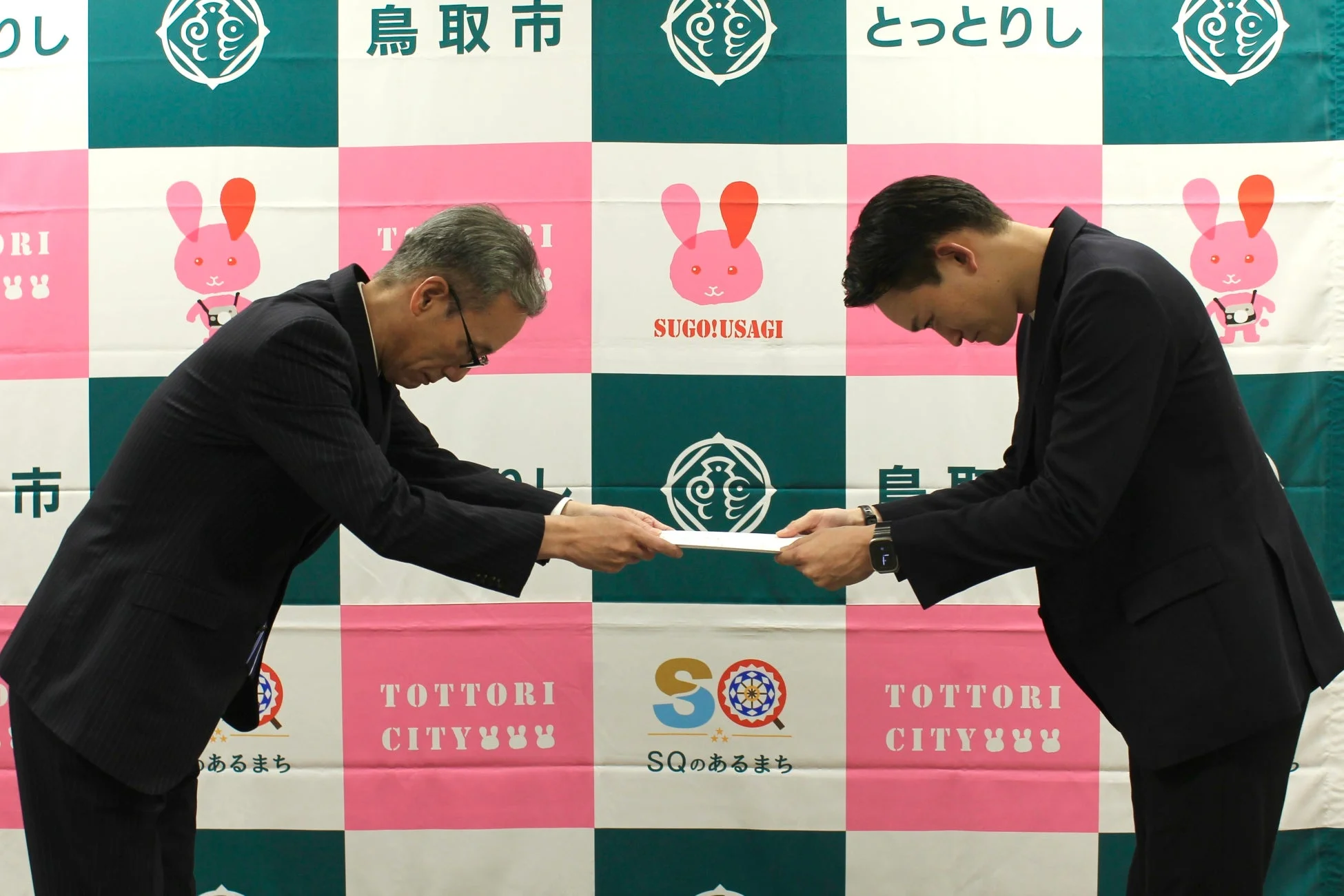 鳥取市役所で書類を授受する2人の男性