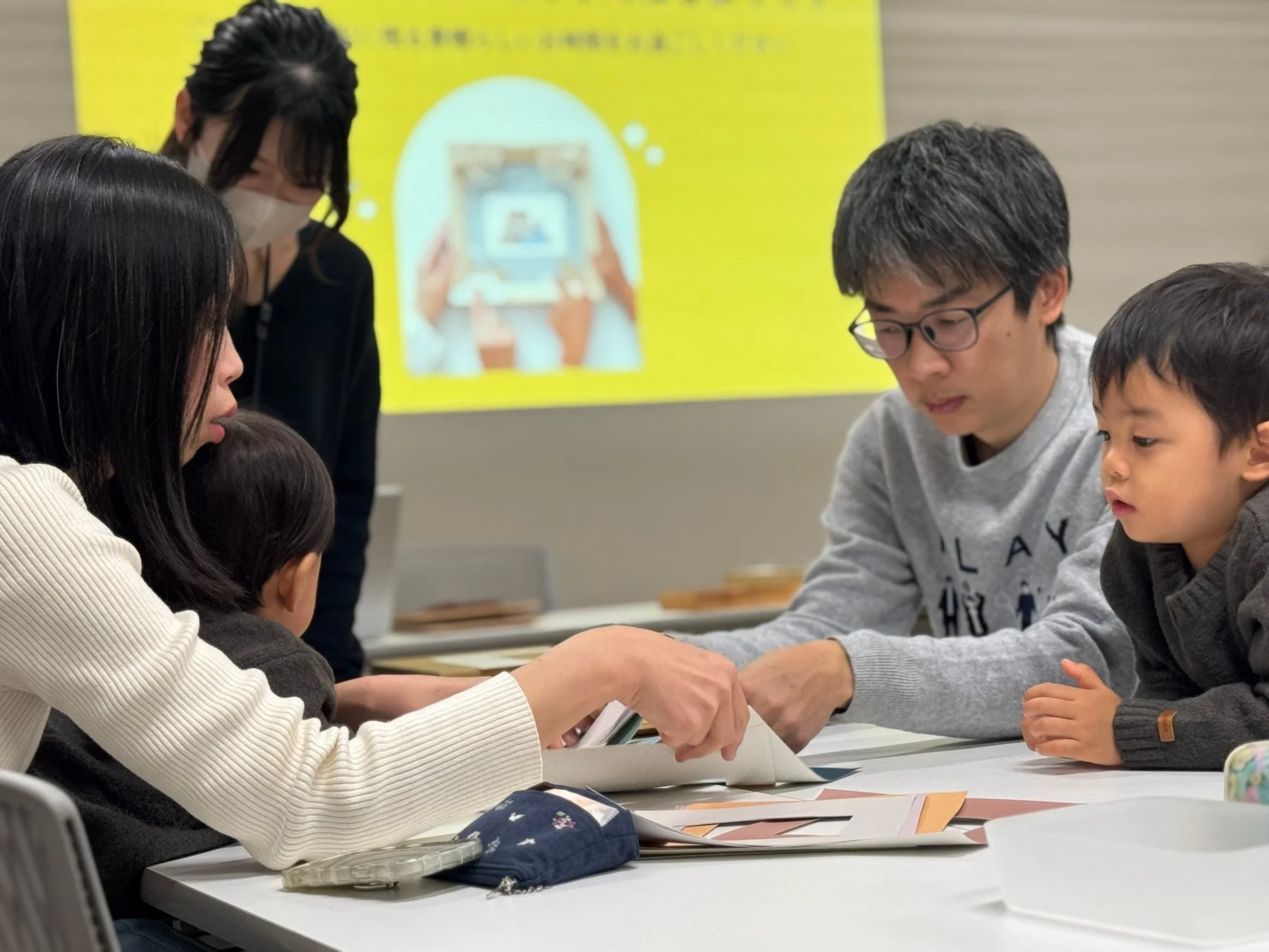 家族がテーブルでクラフト体験を楽しむ様子