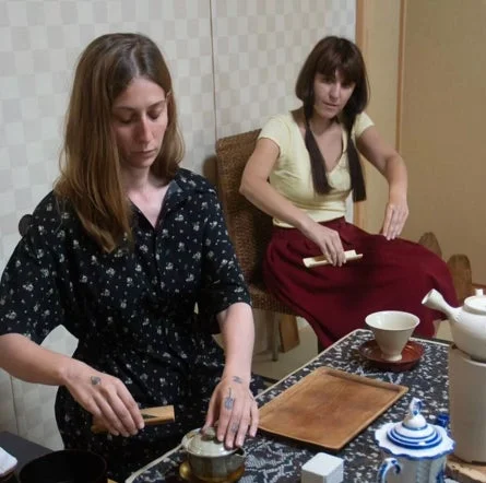 二人の女性が室内で日本の伝統的な茶道を体験している様子