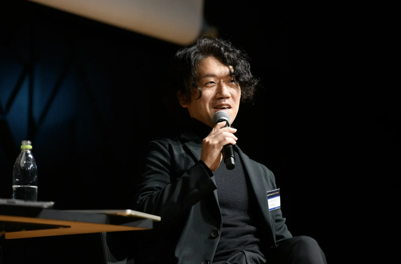 マイクを手に笑顔で話す男性