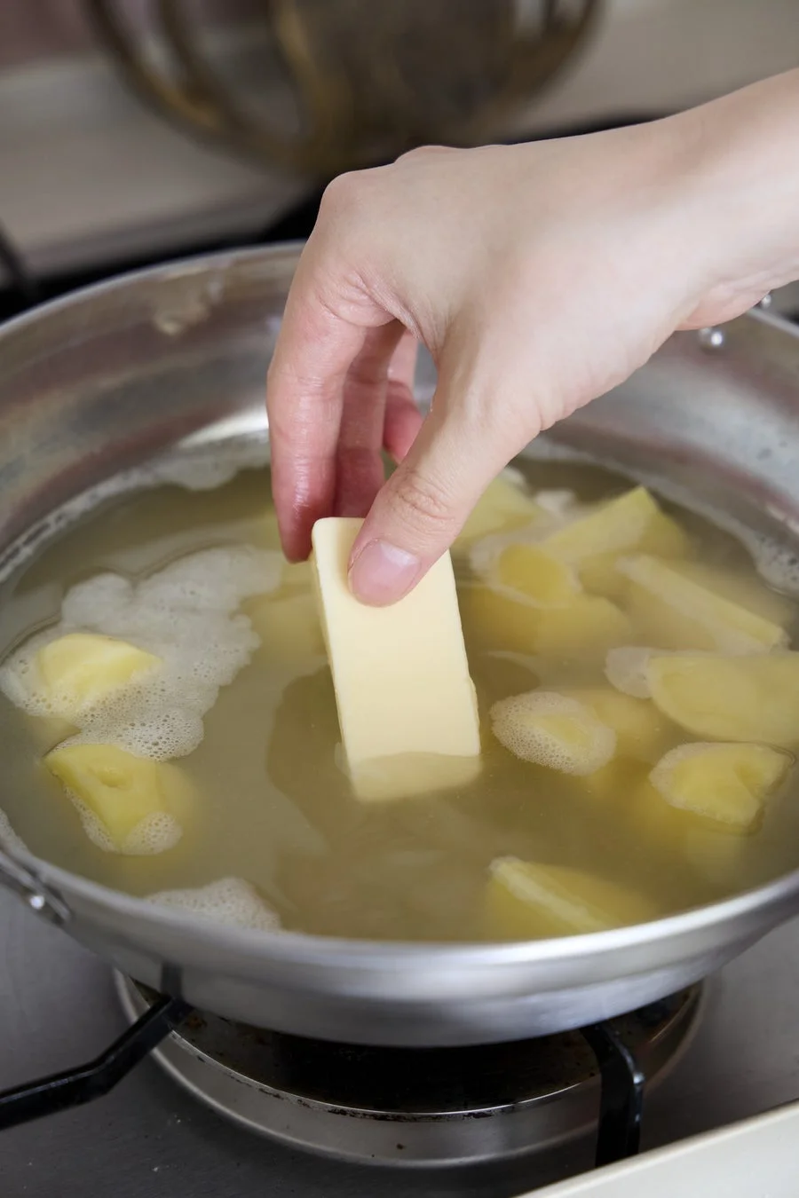 じゃがいもを茹でる鍋にバターを入れる様子