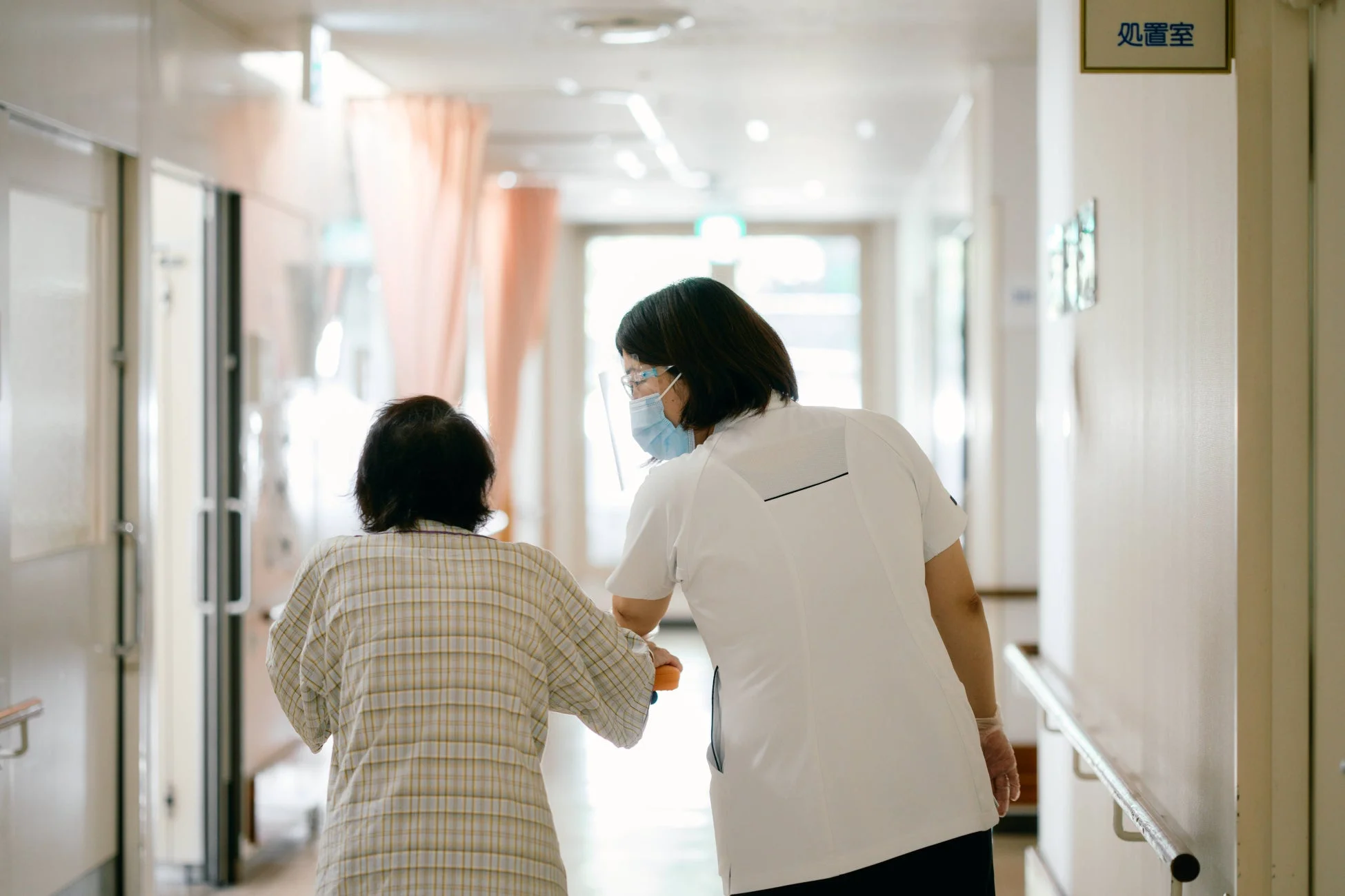 医療従事者が高齢患者の歩行を介助する様子