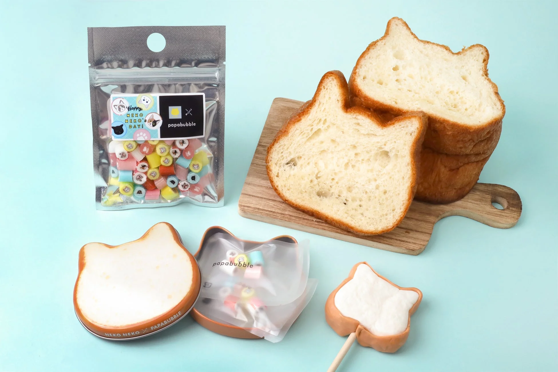 猫の形をしたパン、キャンディ、ロリポップなど、猫モチーフのお菓子が複数並べられた可愛らしい写真です。パパブブレとねこねこ食パンのコラボ商品と思われます。