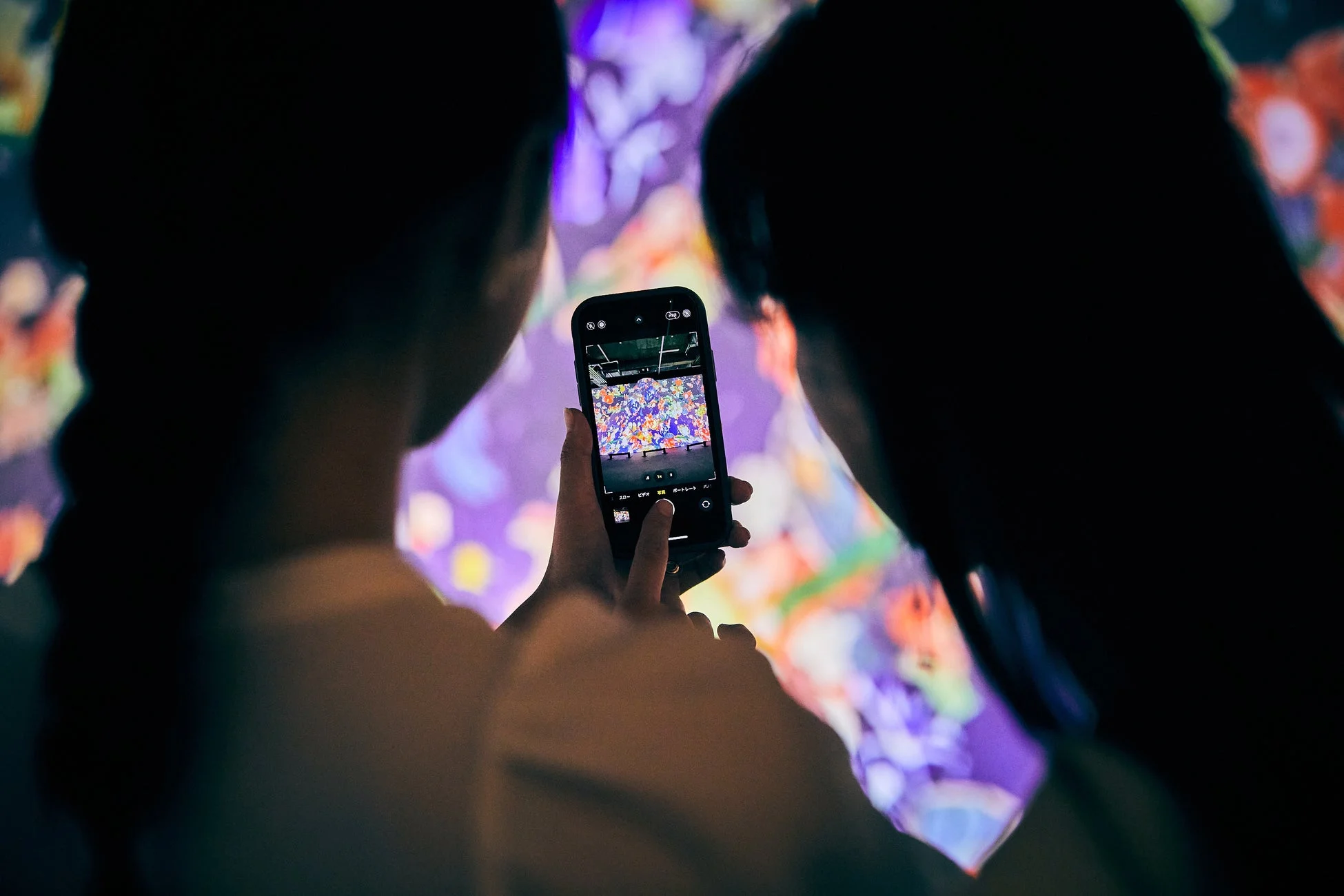 デジタルアートをスマートフォンで撮影する人