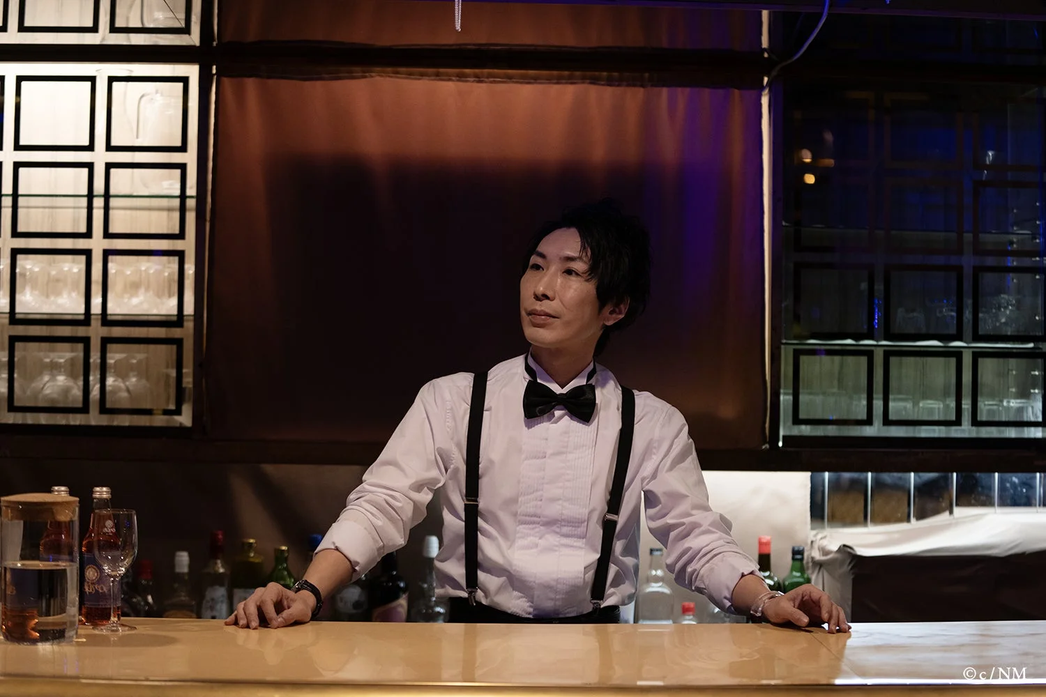 バーカウンターに立つバーテンダー役の男性キャスト