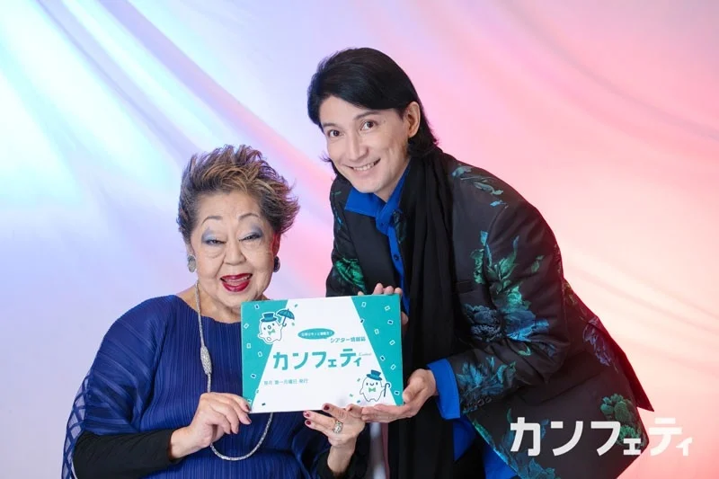 シアター情報誌「カンフェティ」を笑顔で紹介する年配の女性と若い男性のツーショット。