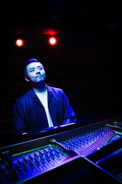 青い照明の下でピアノを演奏する大林武司氏