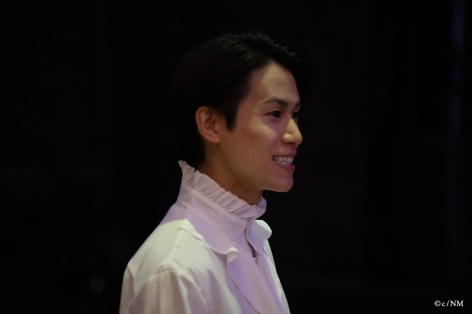 白いラッフルカラーシャツを着て笑顔の男性キャスト