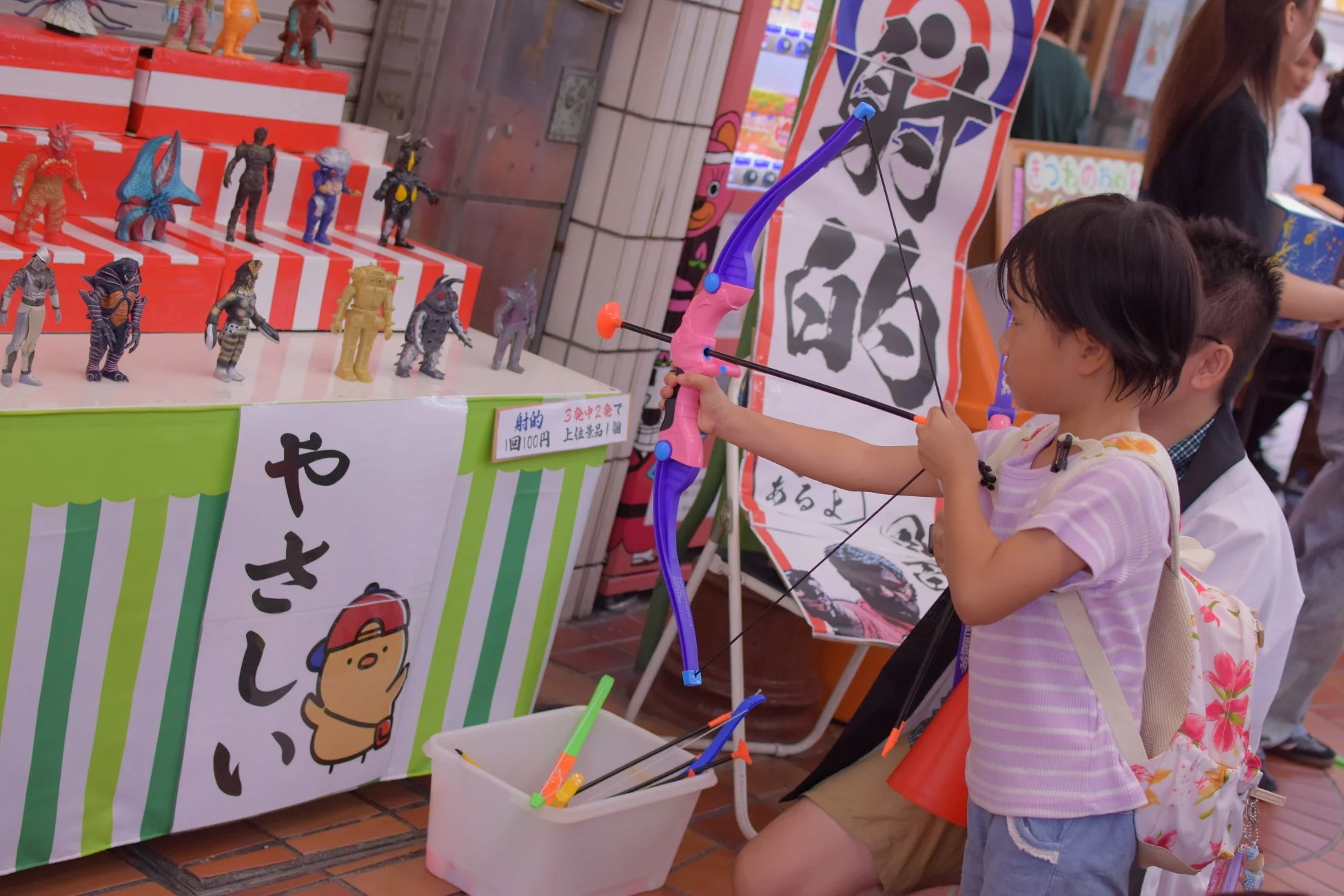 射的の屋台で遊ぶ子ども