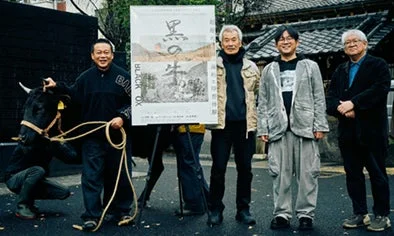 男性が黒い牛とポスターの前に立っている写真