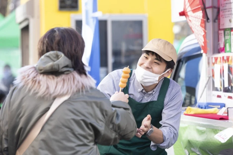 屋台でだんごを手渡す様子