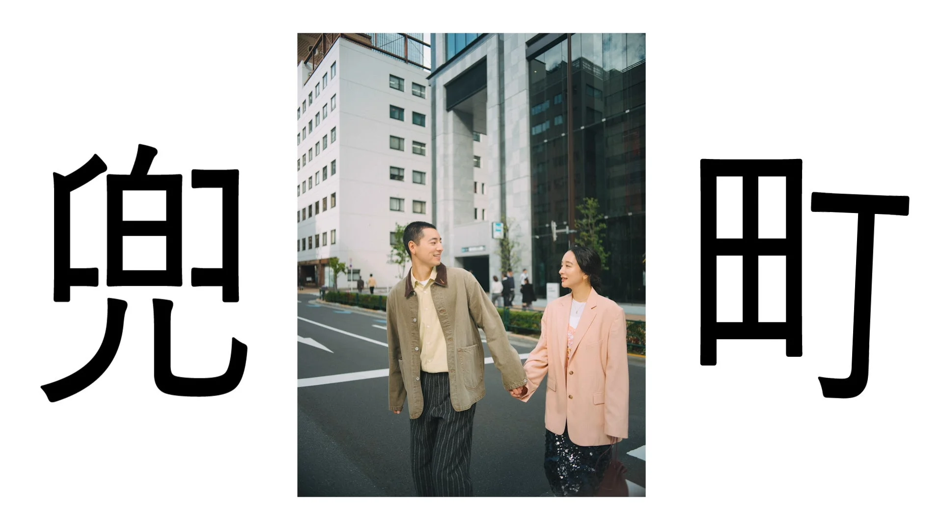 現代的な街並みを背景に手をつないで歩くカップル