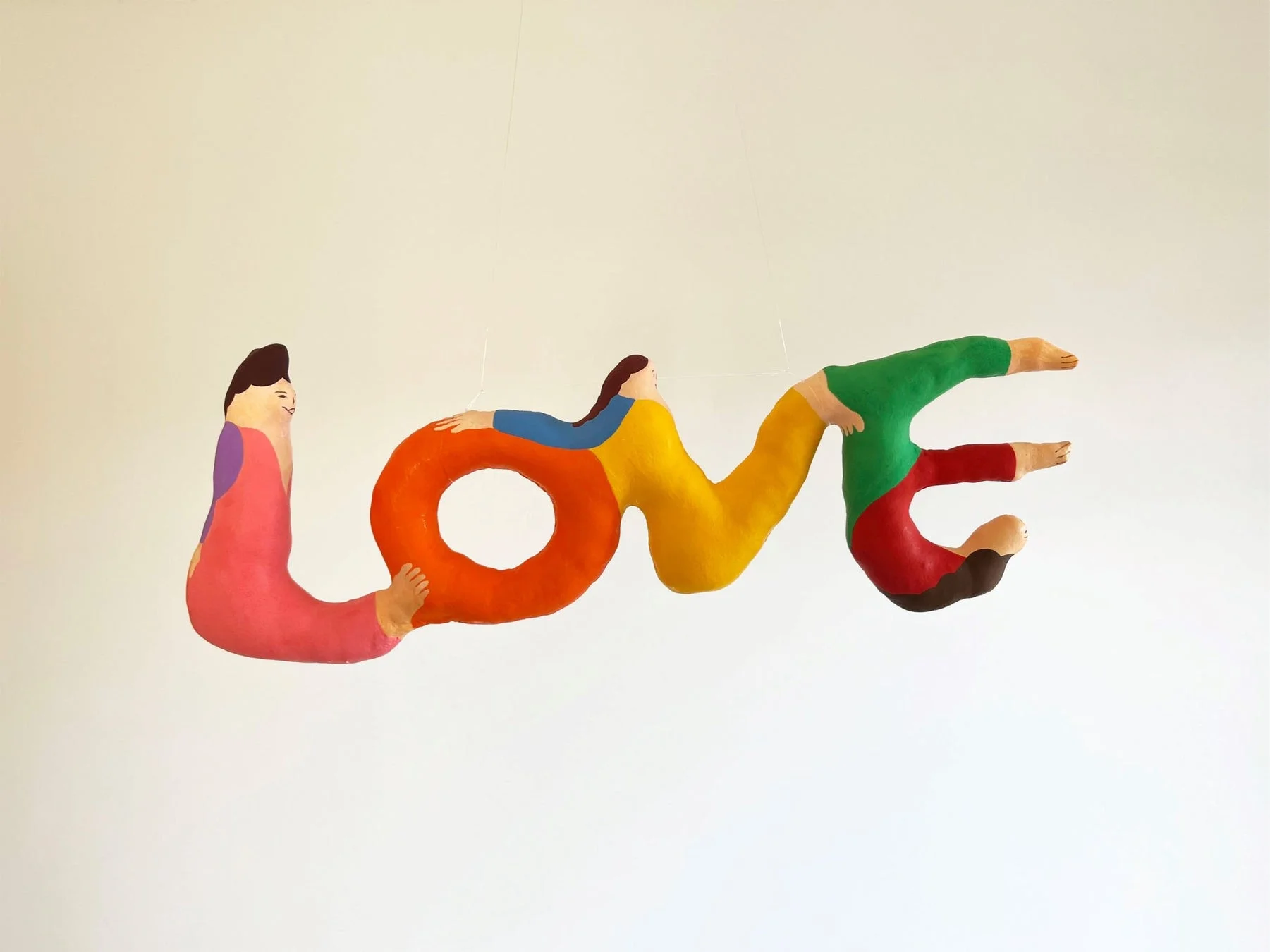 人型オブジェが「love」の文字を形成するカラフルなアート