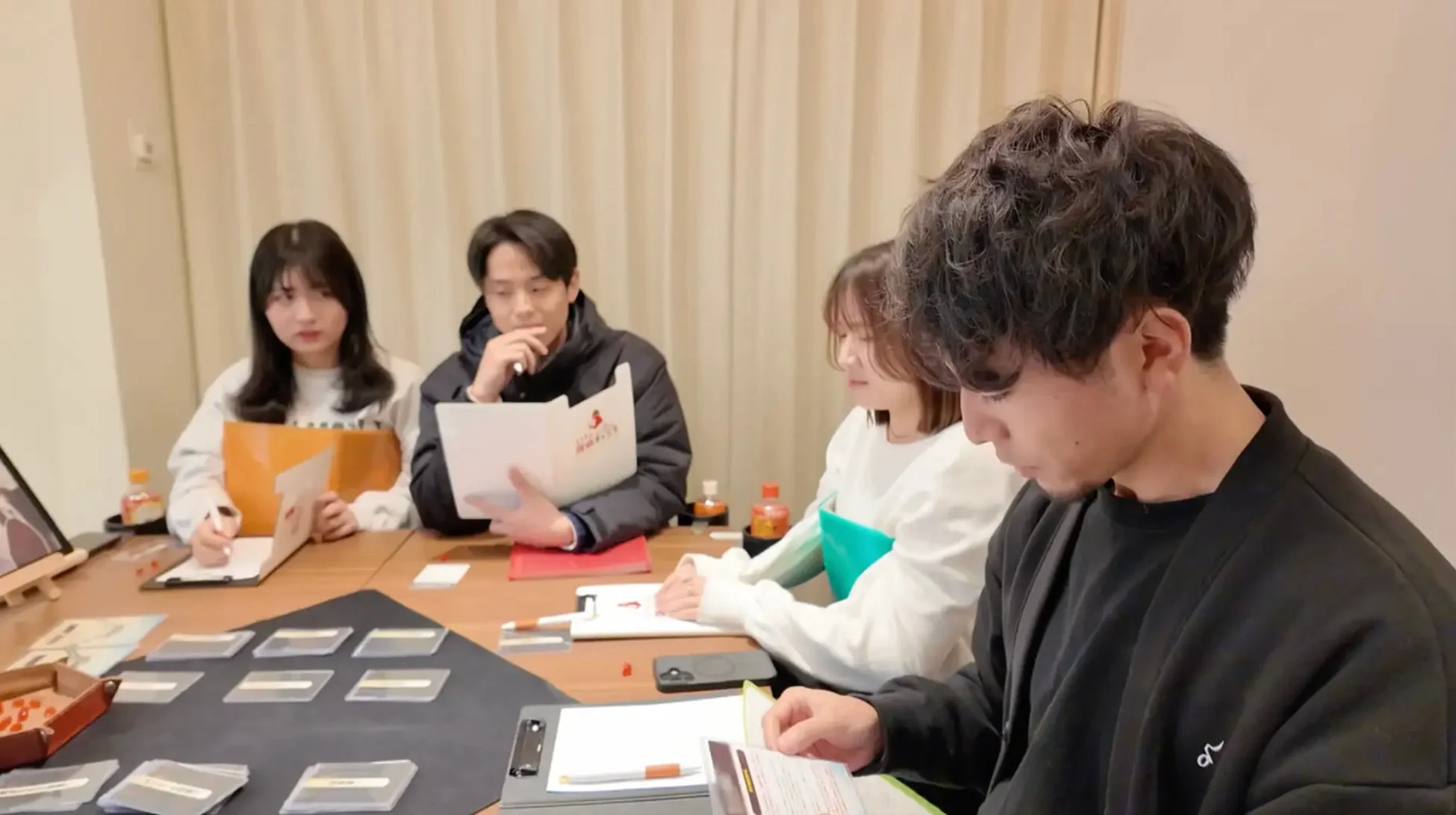 ボードゲームか勉強会のような活動をする4人の若者