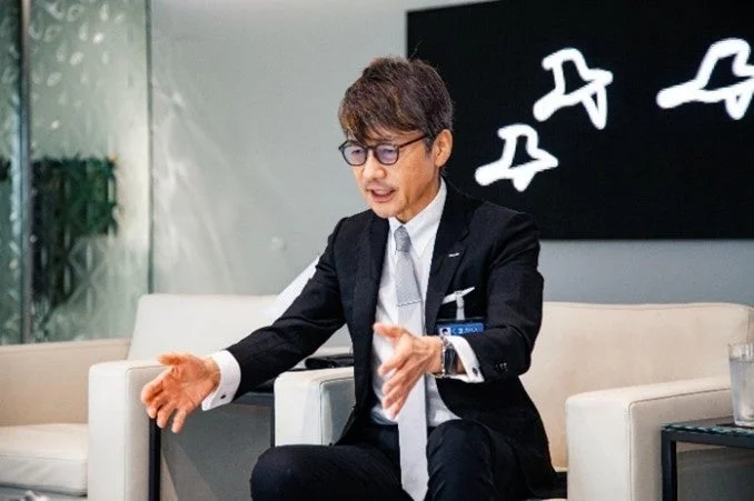 会議室で話す熊谷正寿氏