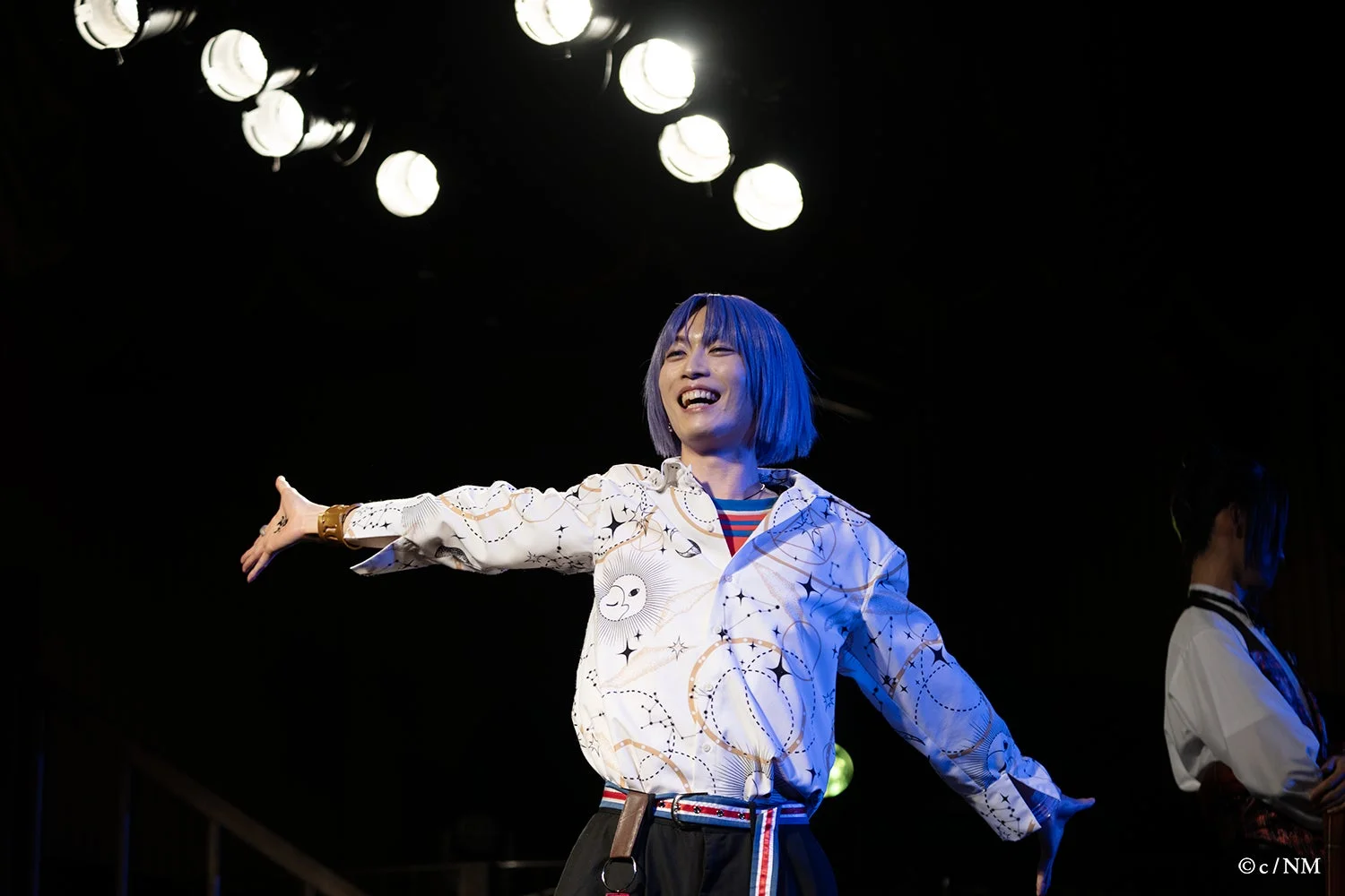 ステージ上で両腕を広げる青い髪の男性キャスト