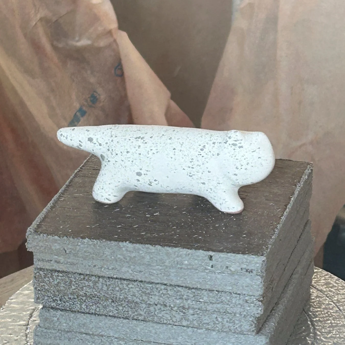 白い斑点模様の動物型置物が、複数の灰色の四角い板が積み重ねられた上に置かれています。シンプルでモダンな雰囲気のオブジェの写真です。