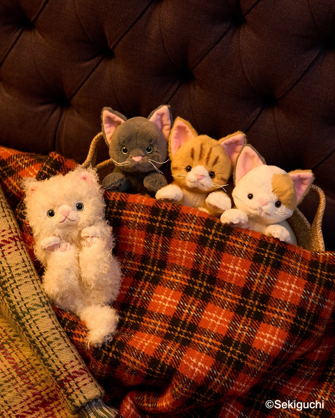 チェック柄のブランケットに集まる4匹の猫のぬいぐるみ