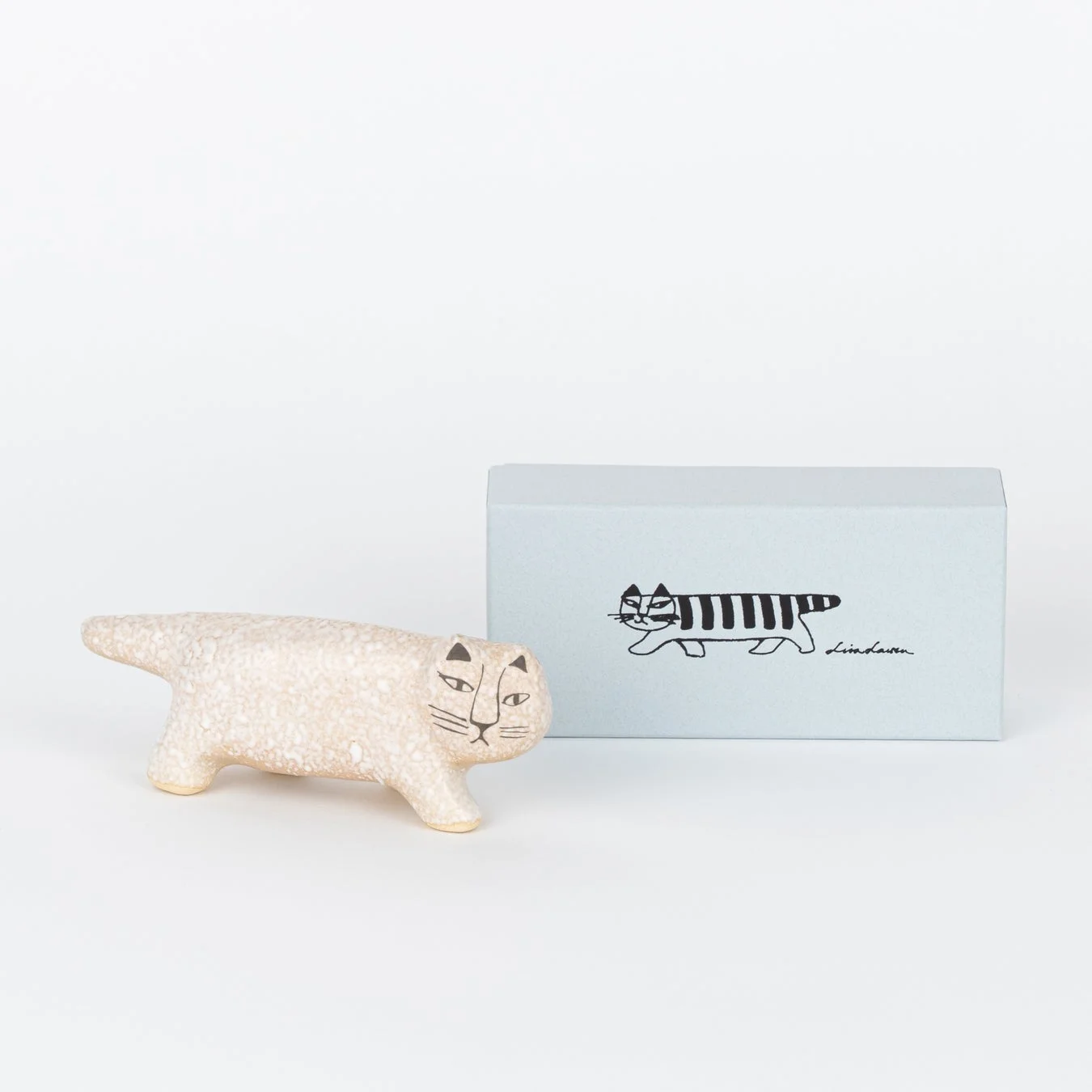 リサ・ラーソンのベージュ色の陶器製猫の置物と、ストライプ柄の猫が描かれた水色の箱が写っています。北欧デザインの可愛らしい猫のオブジェです。