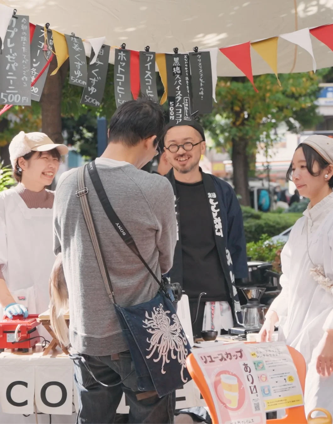 屋外のマーケットで、人々が屋台に集まっている様子