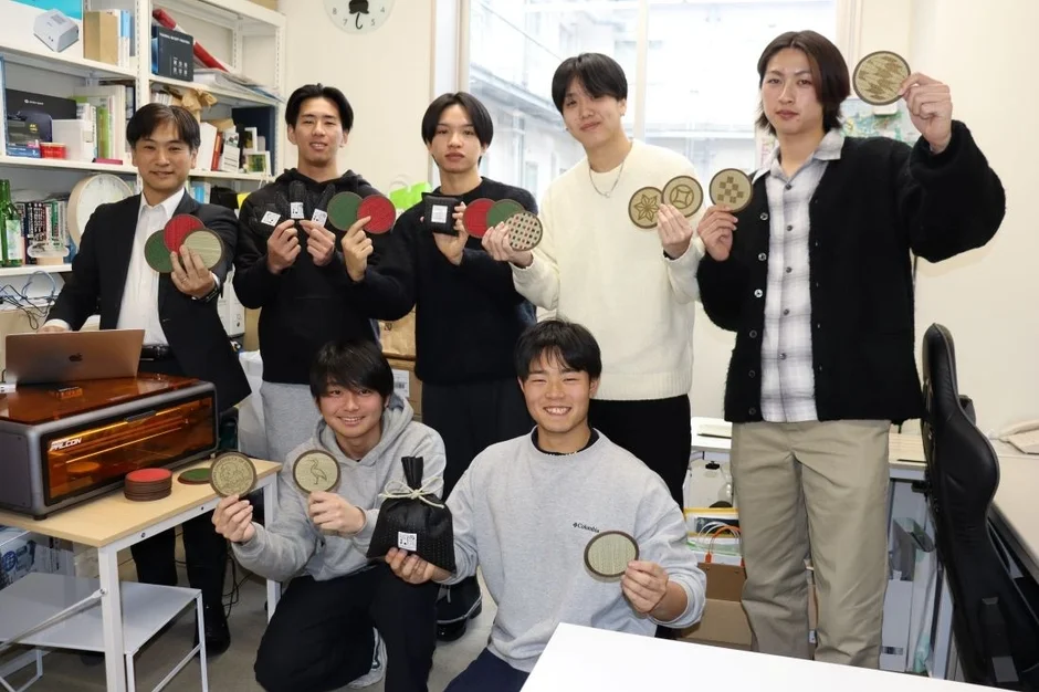 レーザーカッターで製作されたコースターを持つ学生グループ