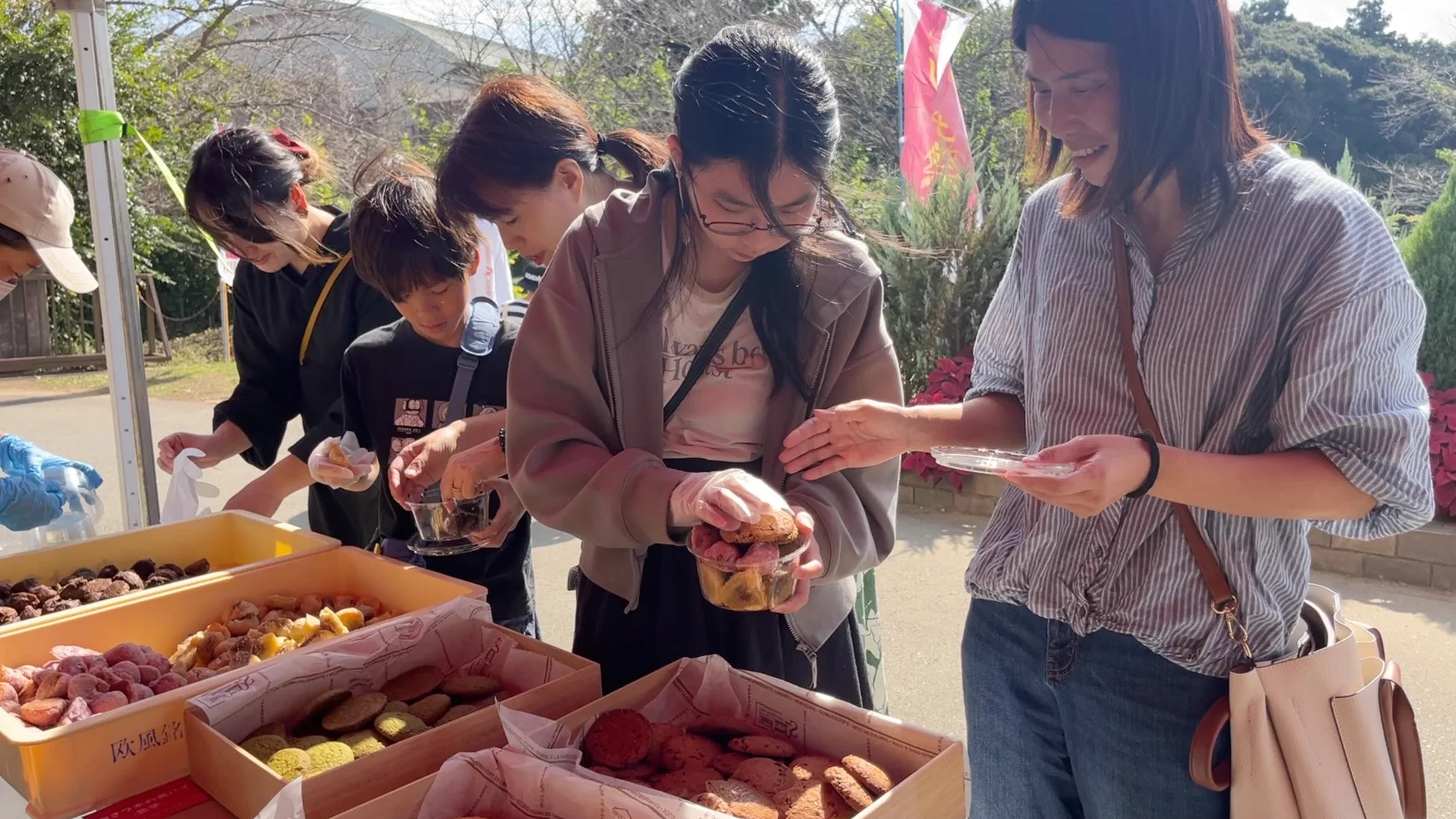 屋外の屋台で焼き菓子を選ぶ人々