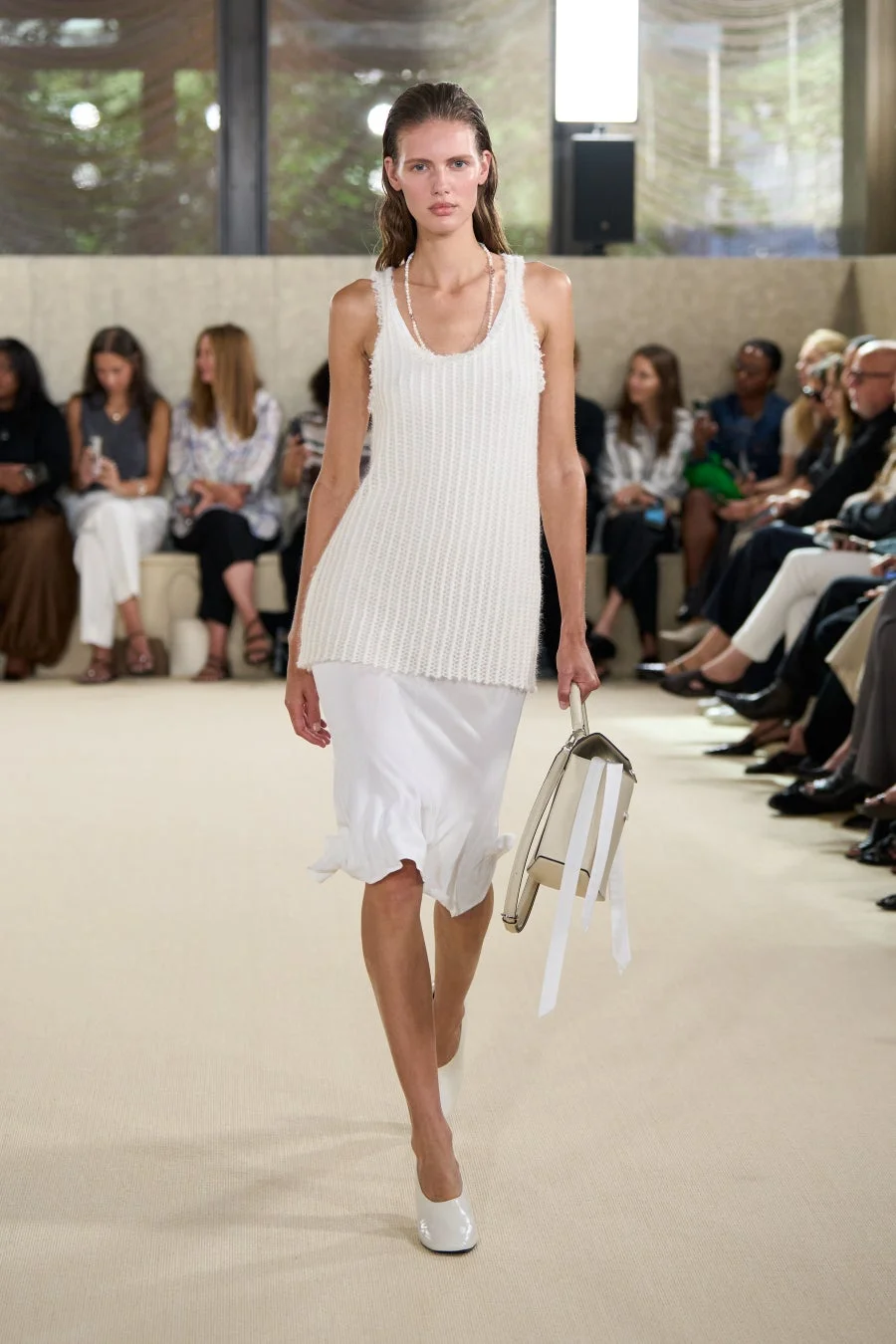 白いニットのタンクトップとスリップスカートを着用したモデル