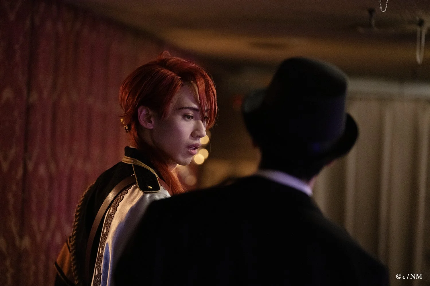 赤い髪の男性キャストと黒いトップハットの人物