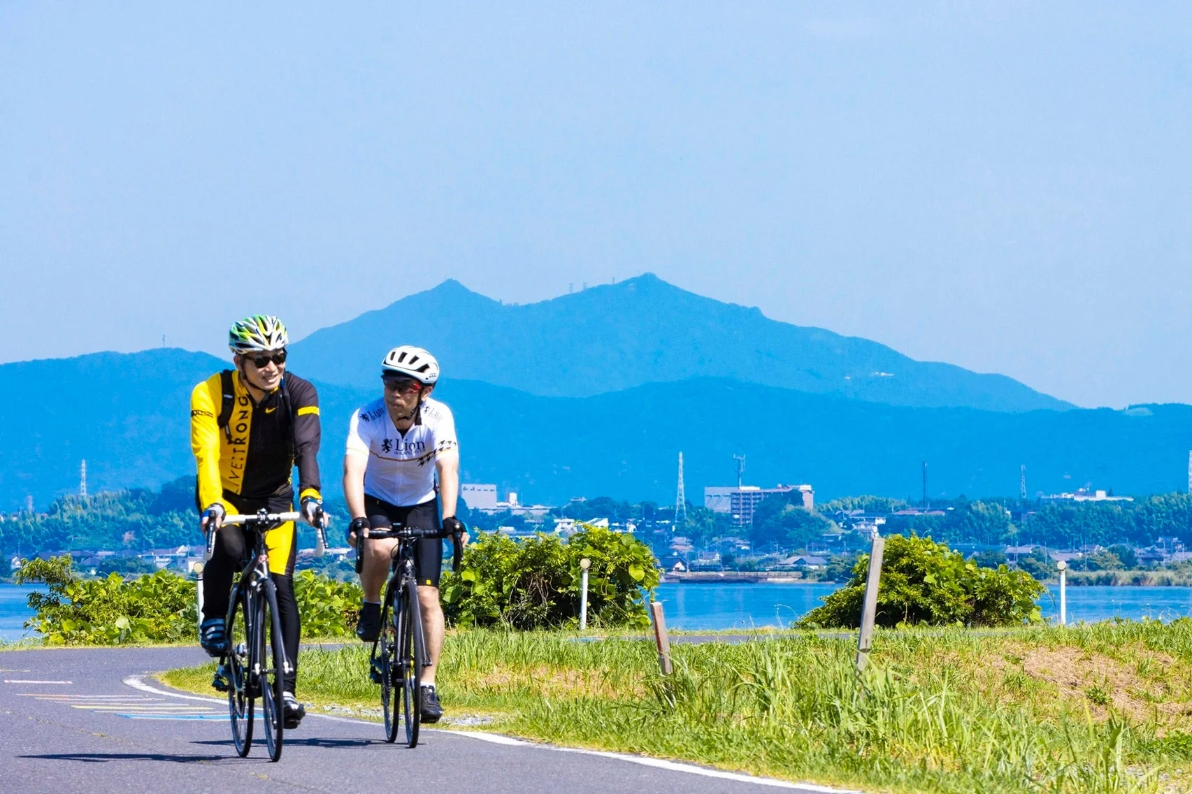 湖畔をサイクリングする2人の男性