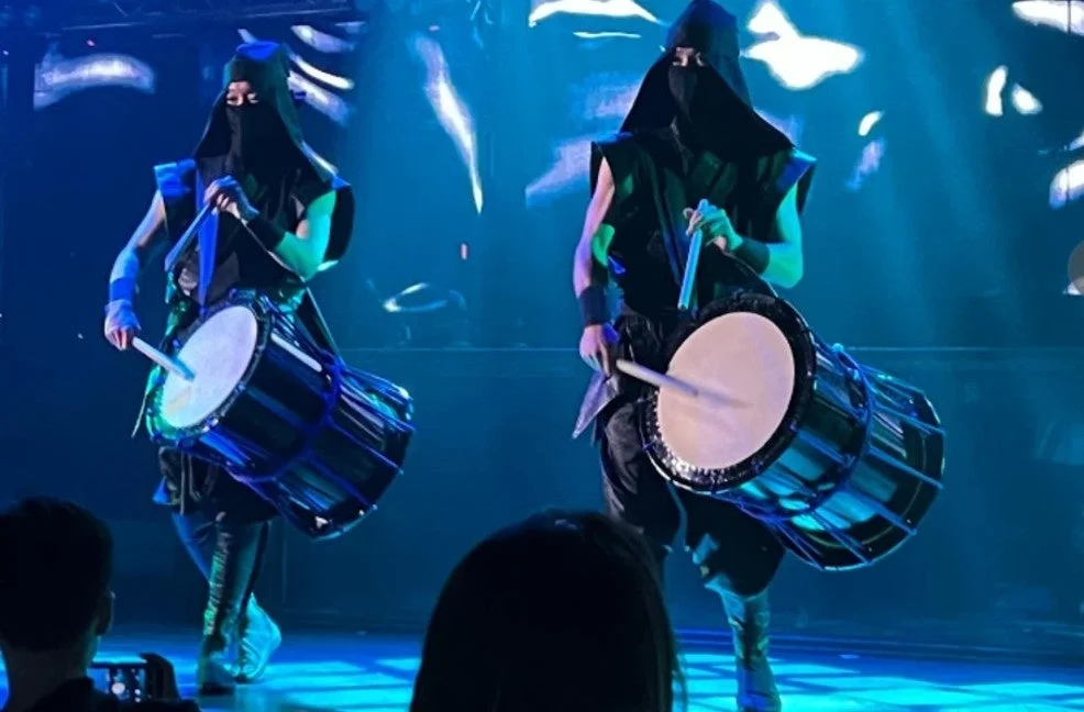 青い照明のステージで和太鼓を演奏するパフォーマー