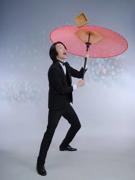 タキシード姿で和傘のバランス芸を披露する石黒ヨンペイ氏