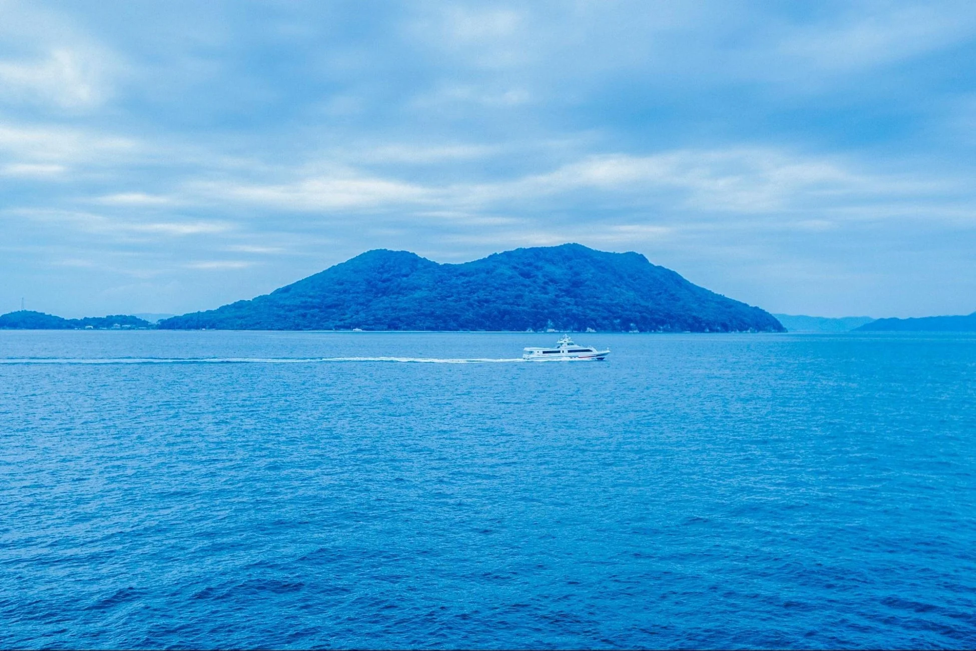 青い海の上を航行する白い船と島々