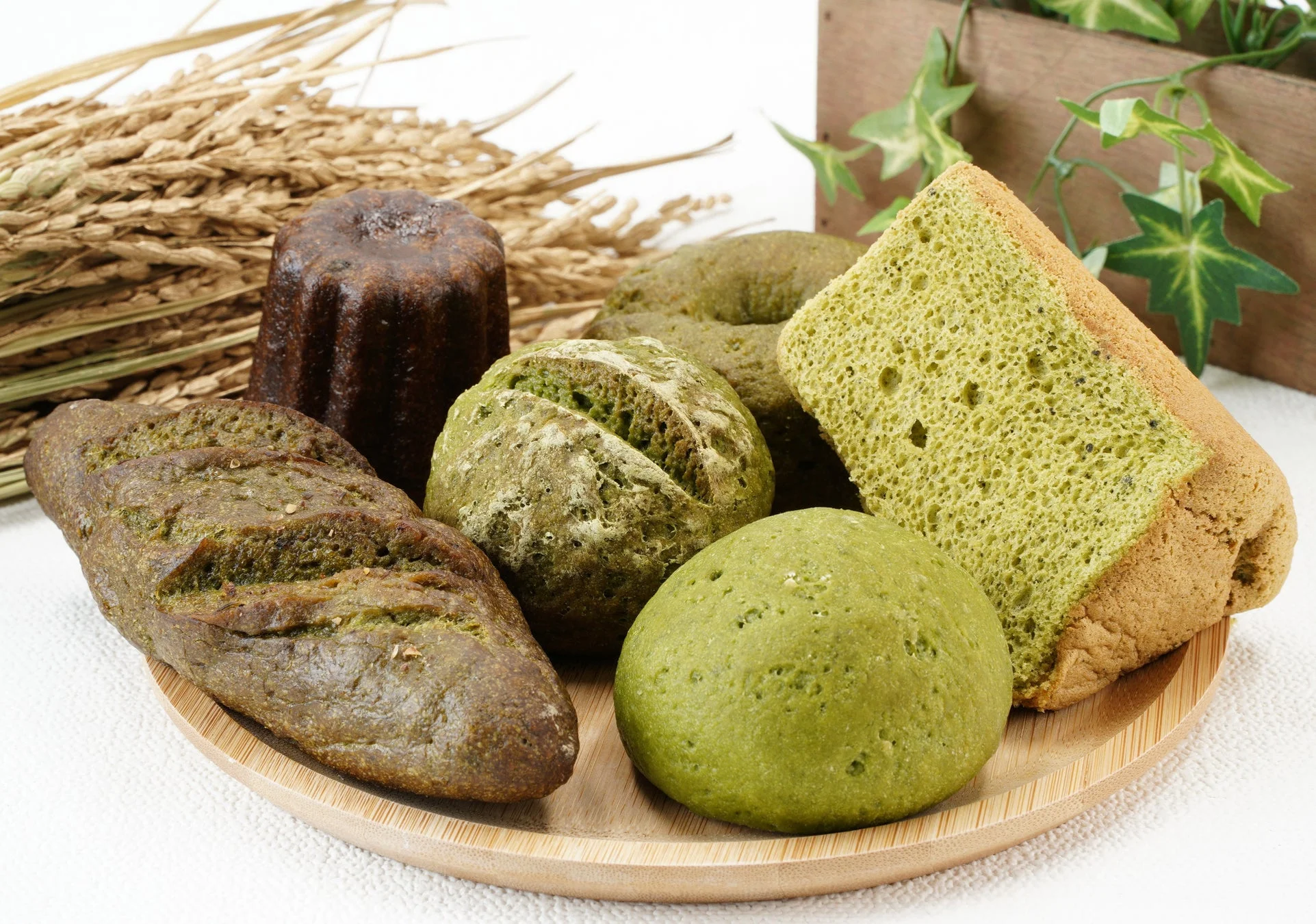 抹茶色のパンやシフォンケーキ、カヌレなどが木皿に盛り付けられた様子