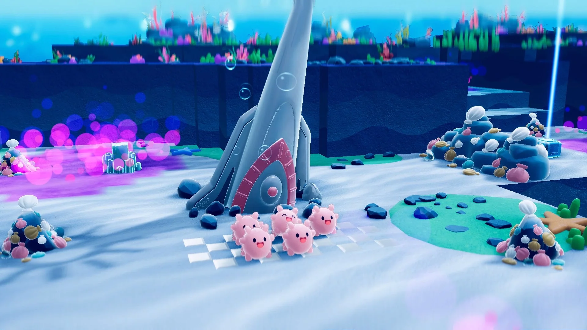 水中のようなファンタジーな世界観のゲーム画面です。白い砂地にはピンク色のかわいいキャラクターが数匹おり、ロケットのような構造物や、カラフルなサンゴ、貝殻が積まれた岩などが配置されています。鮮やかな色彩が特徴的な、かわいらしい雰囲気の画像です。