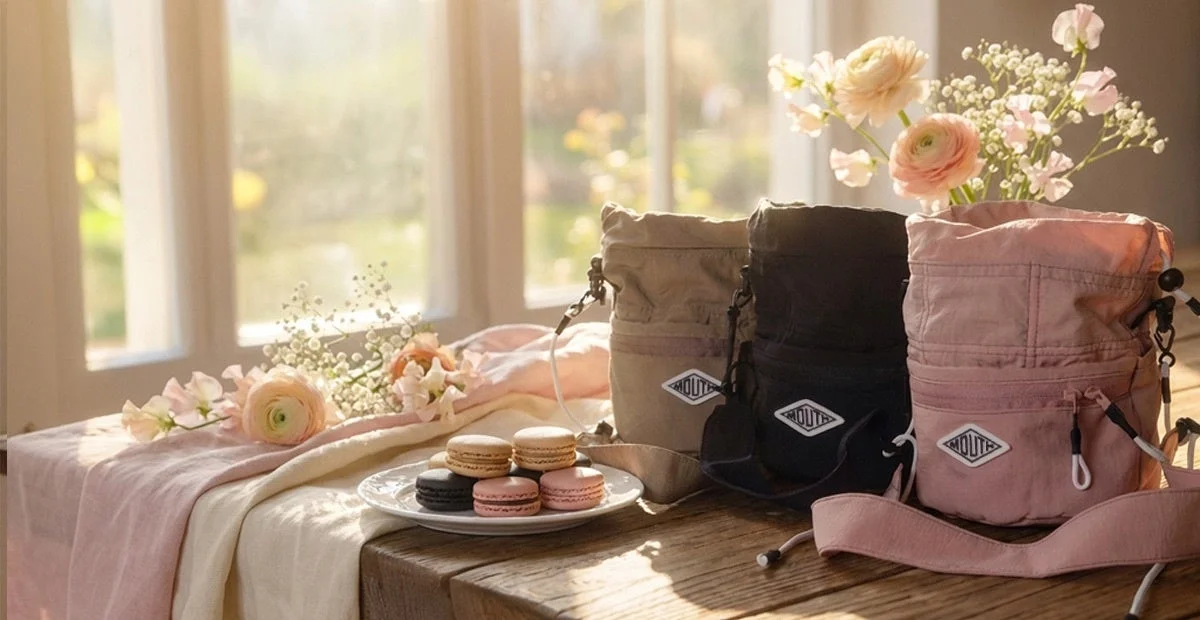 窓辺に並べられた3色の巾着型ショルダーバッグとマカロン、花