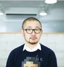 眼鏡をかけ、ひげを生やした短髪の男性