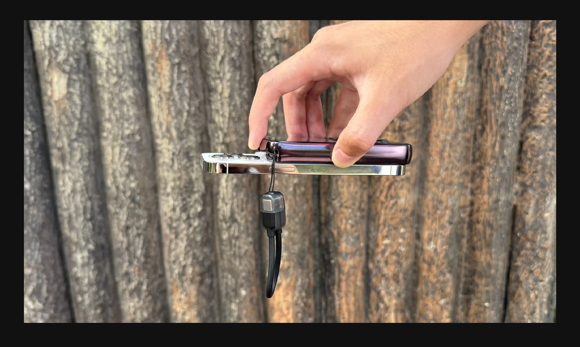 手がiPhoneと折りたたみ式のガジェットを木目の背景の前で持っている様子