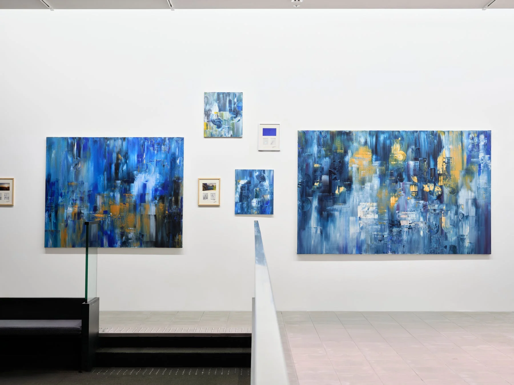 青と黄色を基調とした複数の抽象絵画が展示されたギャラリー空間