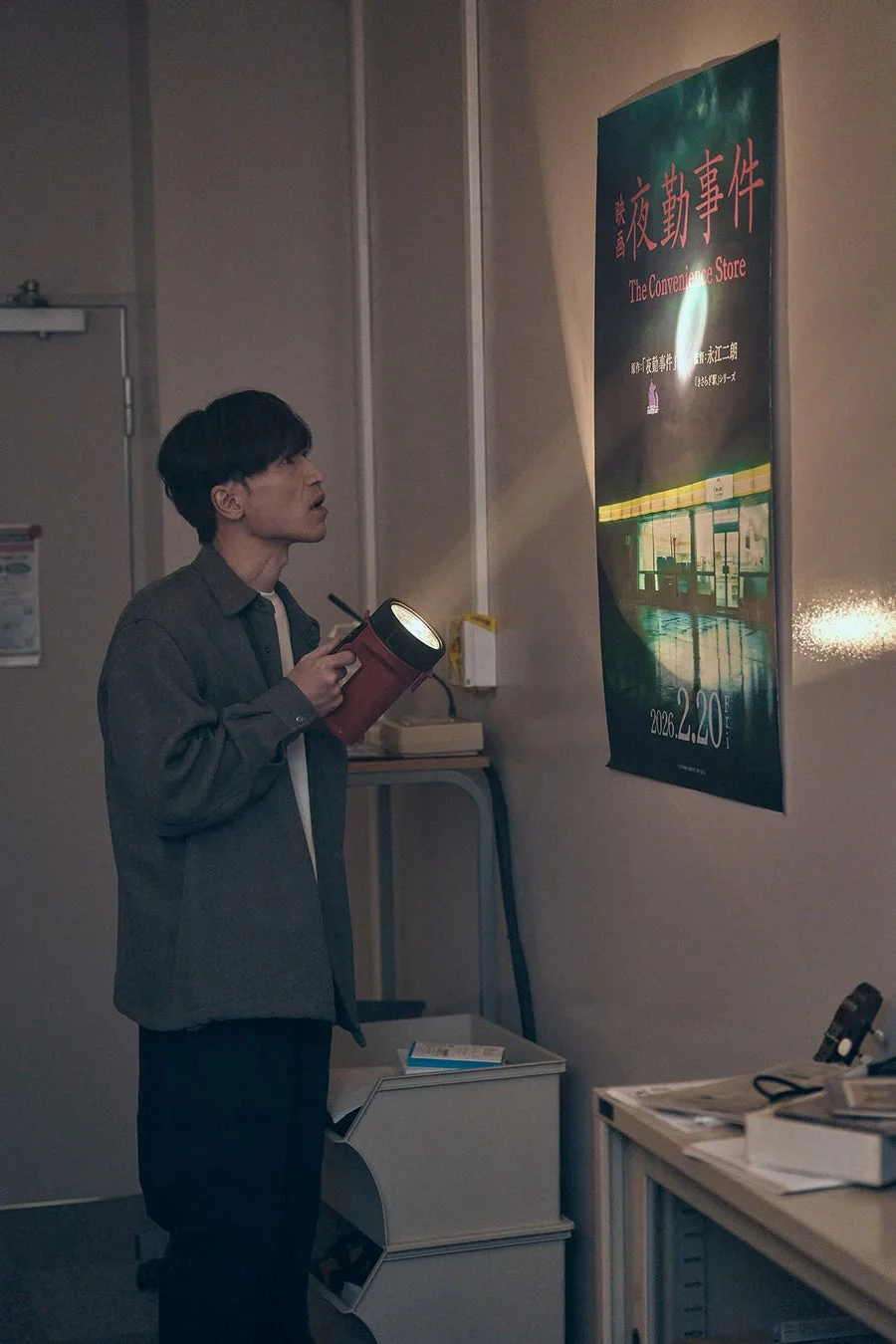 男性が映画『夜勤事件』のポスターを見つめる場面